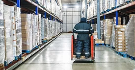 Warehouse worker operating pallet jack in cold storage logistics