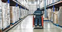 Warehouse worker operating pallet jack in cold storage logistics