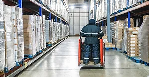 Warehouse worker operating pallet jack in cold storage logistics