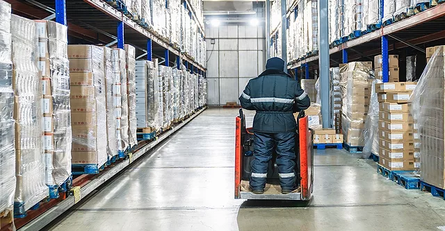 Warehouse worker operating pallet jack in cold storage logistics