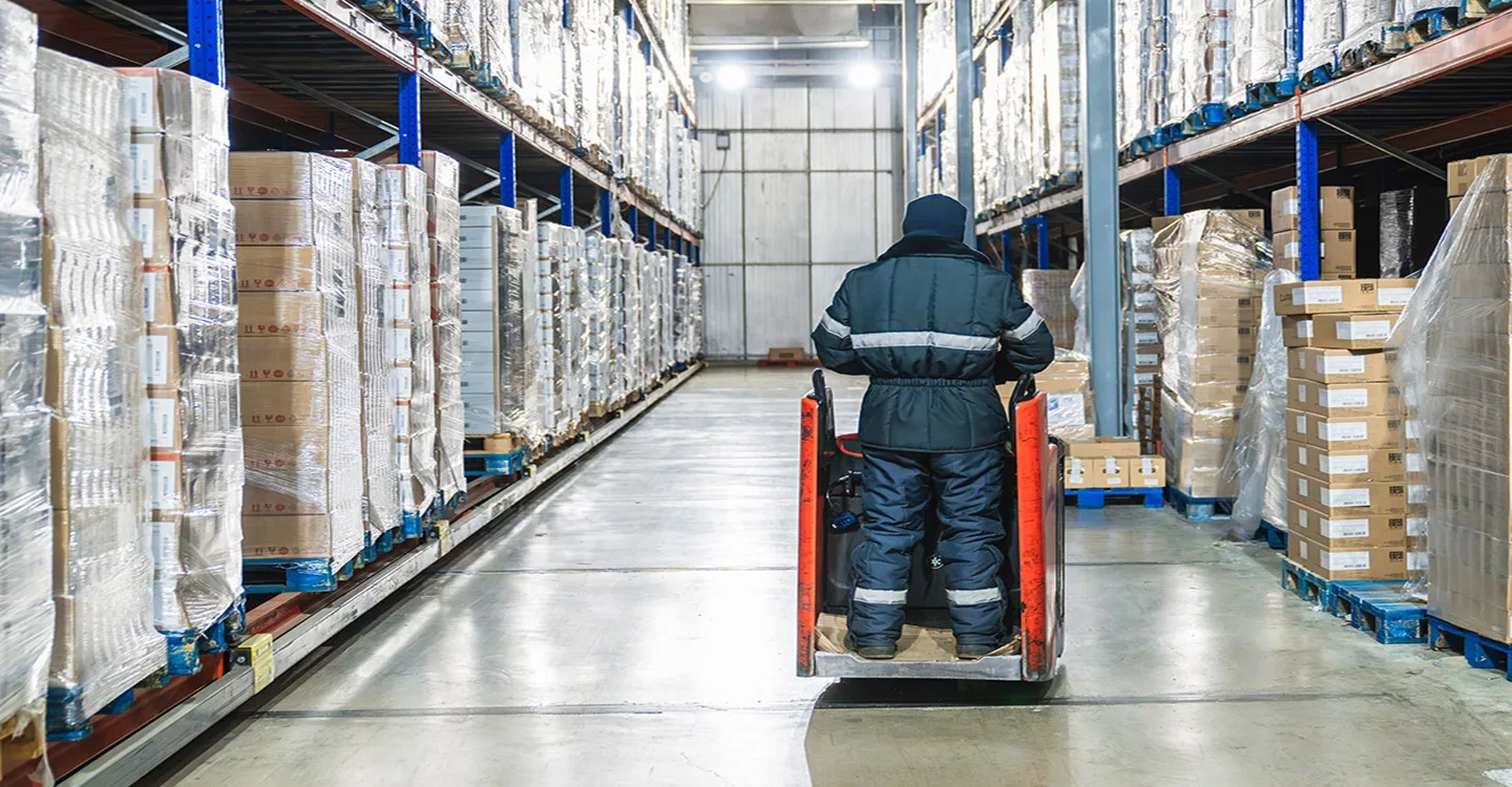 Warehouse worker operating pallet jack in cold storage logistics