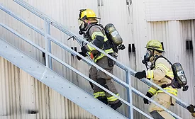 wo firefighters in protective gear climbing stairs