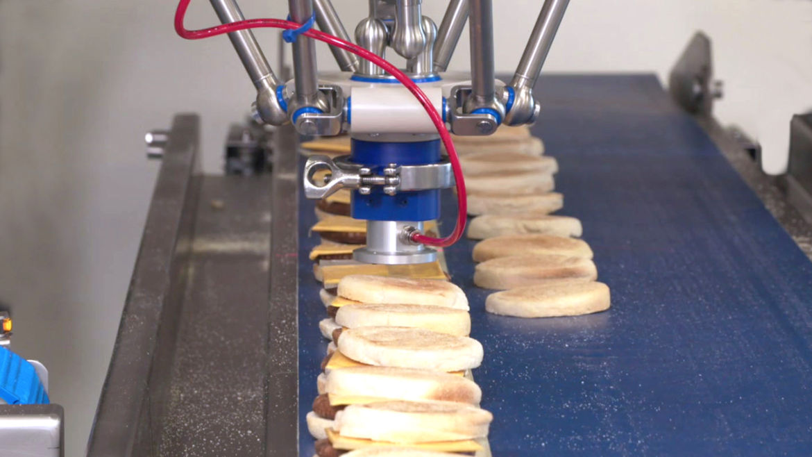Robotic machinery assembles biscuit burger sandwiches