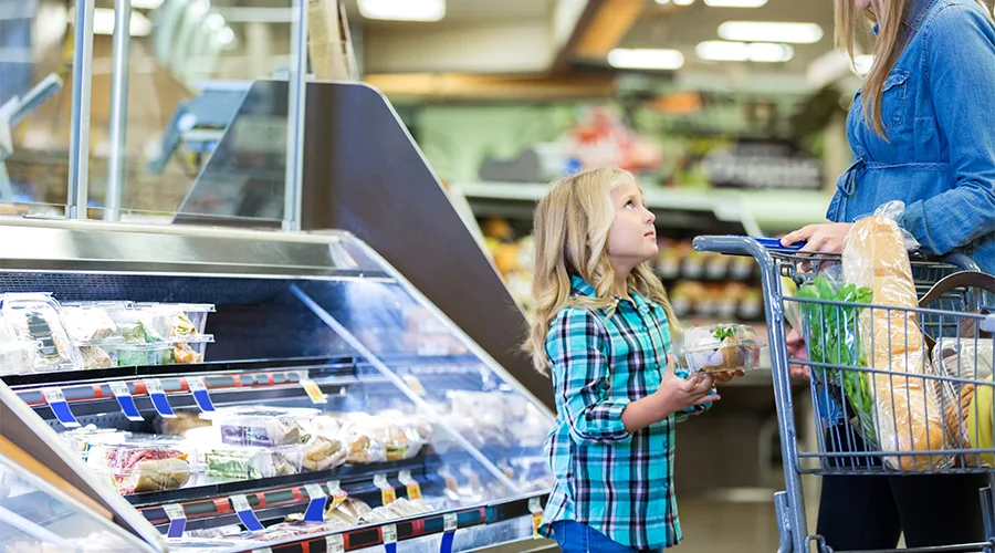 Mom and child shopping in refrigerated food case