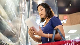 Woman looking at frozen food along the cold produce aisle.
