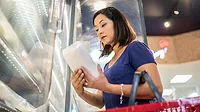 Woman looking at frozen food along the cold produce aisle.