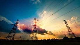 Electric towers with a beautiful cloudy sky at dusk in the background.