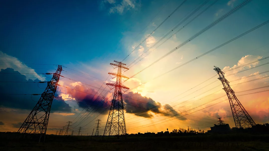 Electric towers with a beautiful cloudy sky at dusk in the background.