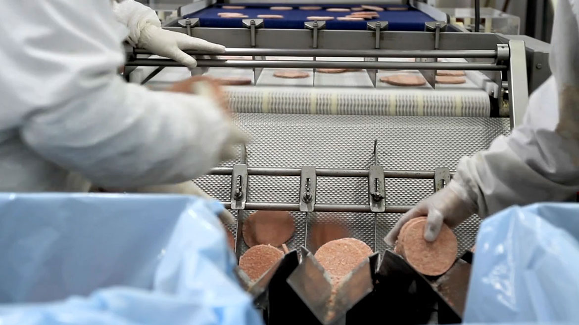 Workers packaging frozen hamburger patties.