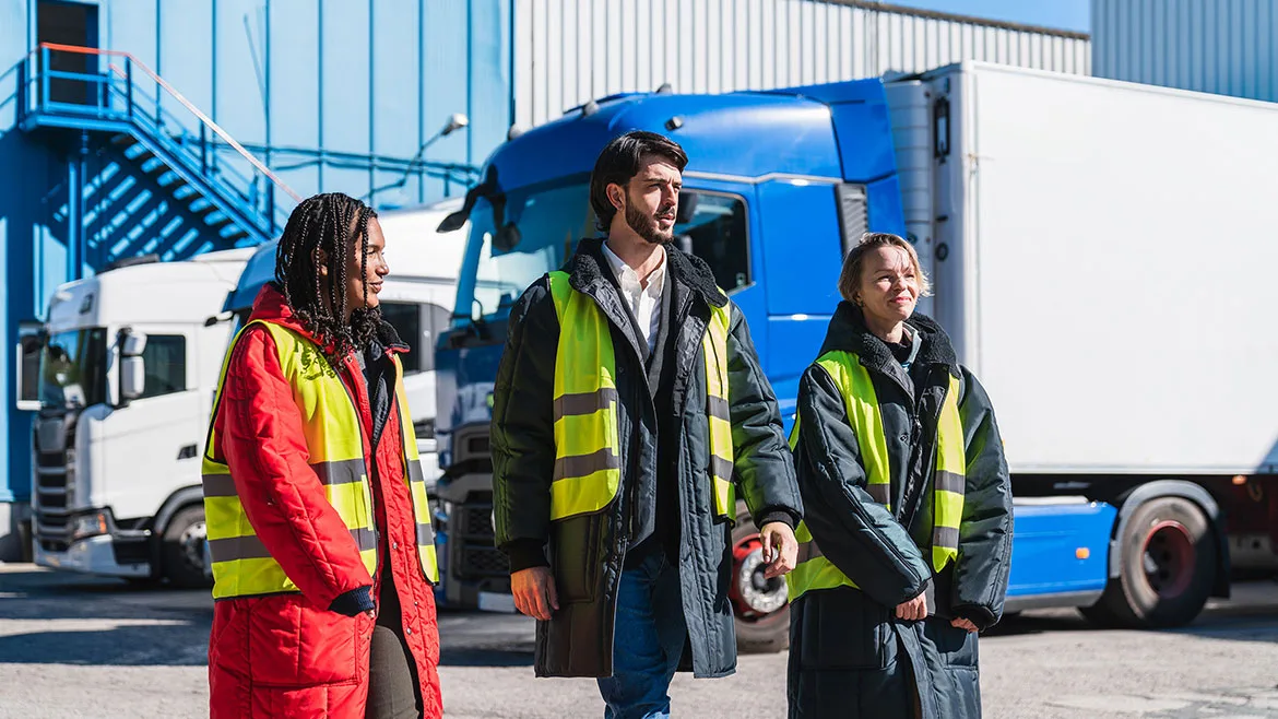 a diverse logistics team standing in front of parked refrigerated trucks