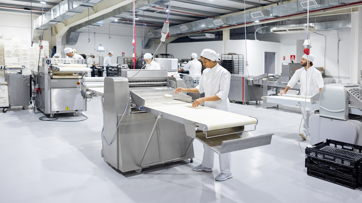 Group of employees working in the production line at an industrial bakery.
